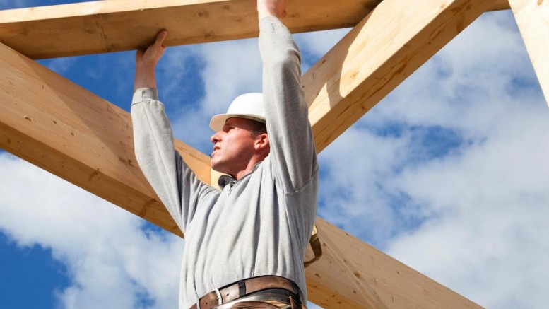 man-lifting-wooden-beams-against-blue-sky