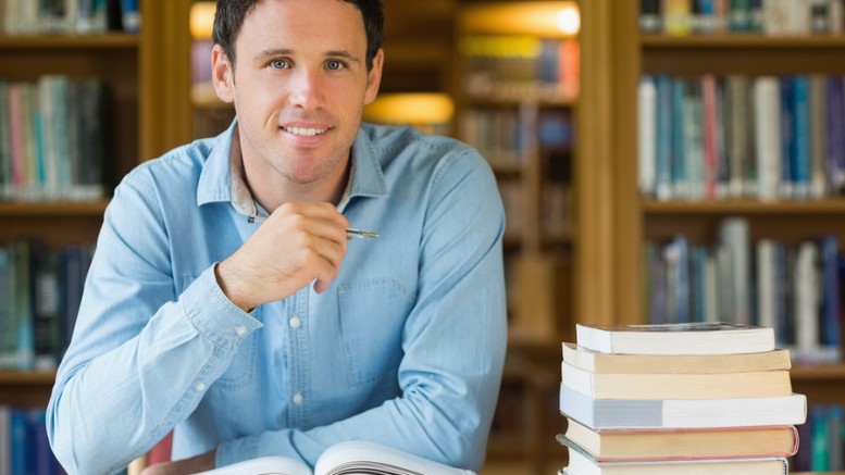 Portrait of a smiling mature male student studying at desk in th