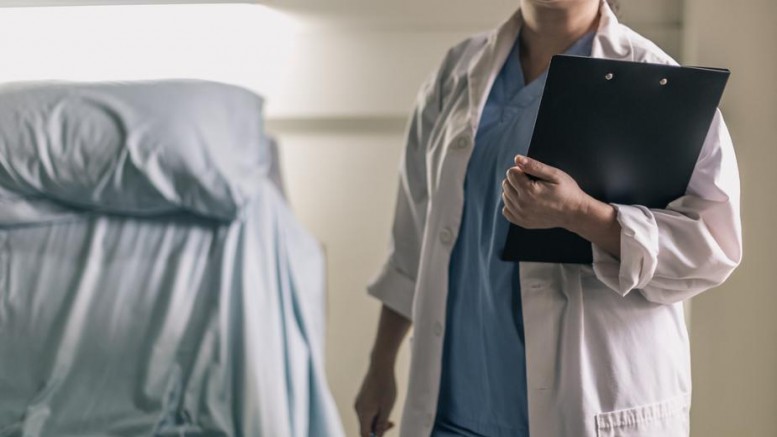 medical-professional-in-scrubs-holding-clipboard-and-pen