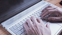 Close-up of male arm, typing on laptop