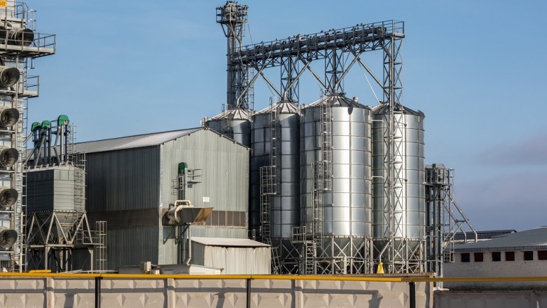 agro silos granary elevator in winter day in snowy field. Silos on agro-processing manufacturing plant for processing drying cleaning and storage of agricultural products, flour, cereals and grain.