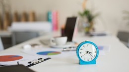 Close up blue alarm clock on desk in modern office